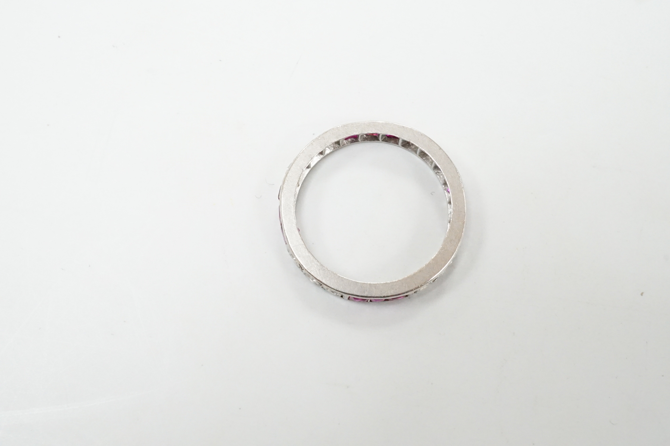 A white metal, ruby and diamond set full eternity ring, size L/M, gross weight 3.1 grams.